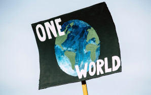 Demonstrationsplakat mit einer Erdkugel und dem Schriftzug ONE WORLD