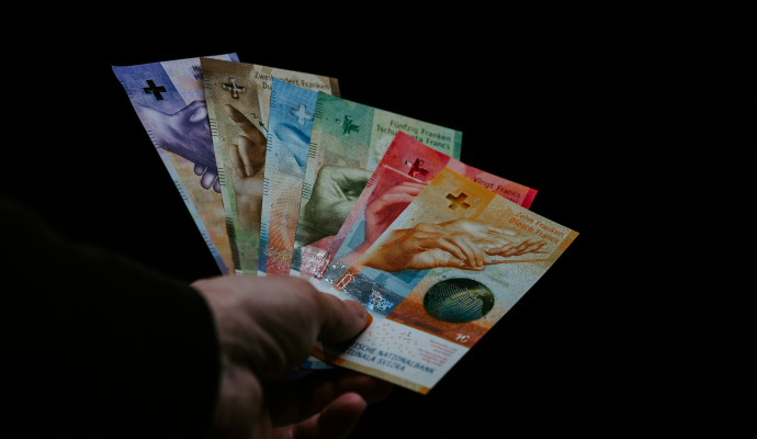 Eine Hand, die alle sechs verschiedenen Schweizer Banknoten gefächert in einer Hand hält